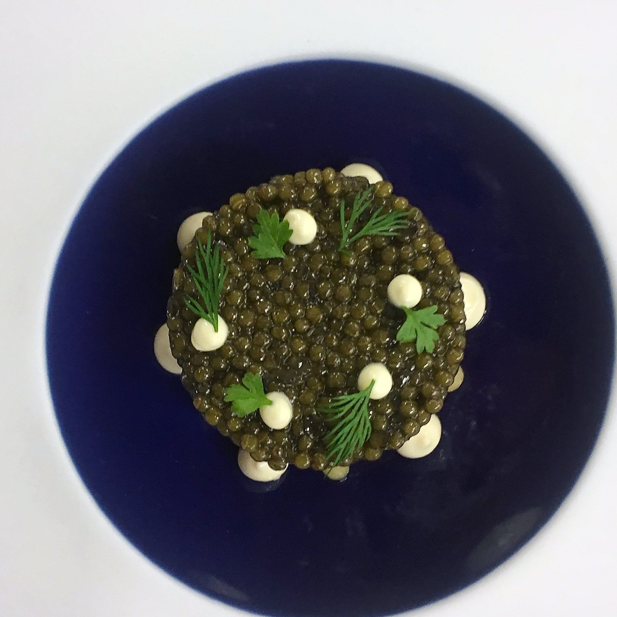 Caviar with crème fraîche on a blue plate