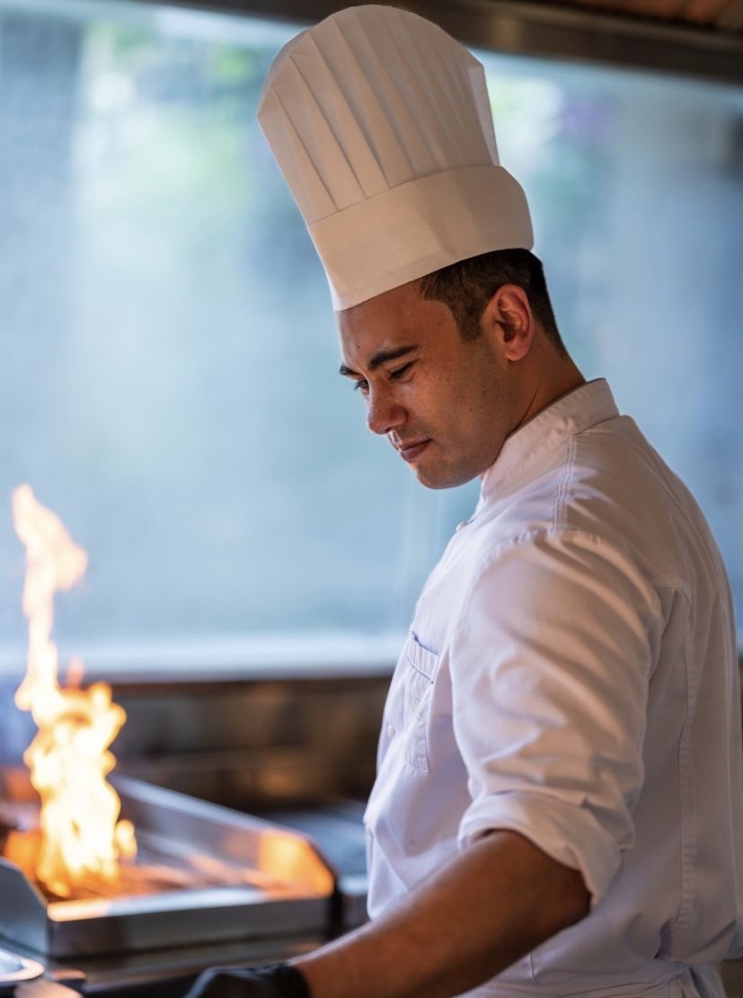 Nicholas Gannaway at the grill, flames beside him